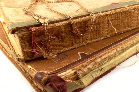 Gold chain with a cross on a background of old battered books