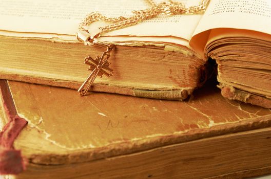 Gold chain with a cross on a background of old battered books