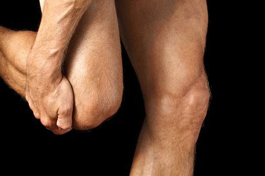 Closeup of man grasping his knee while walking on black background