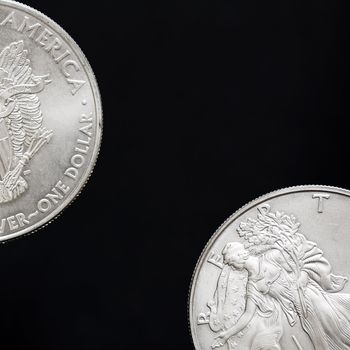 Two silver shiny dollar coins isolated on black background