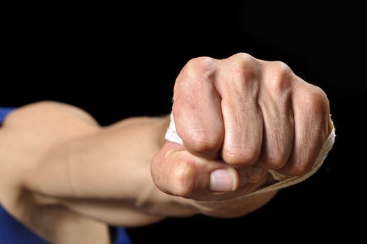 Closeup of muscular man throwing fist at camera on black background