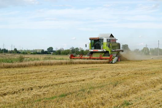 BIRZAI, LITHUANIA - CIRCA AUGUST - combine machine equipment pass harvest wheat crop in agricultural field and stork look for food on circa August, 2012 in Birzai, Lithuania.