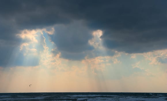 Sun behind dark storm clouds over the sea