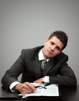 Young businessman tired of paperwork looking at camera