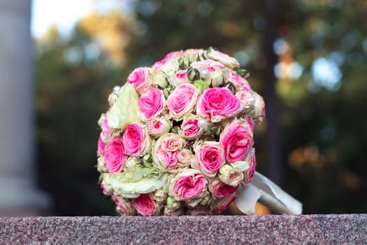 The forgotten wedding bouquet from roses lays on a granite stone
