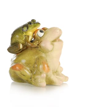 bullfrog sitting on the back of a ceramic frog isolated on white background
