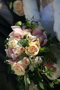 Wedding bouquet from beige roses on a background of a wedding dress