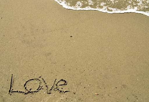 Love written in the sand with wave