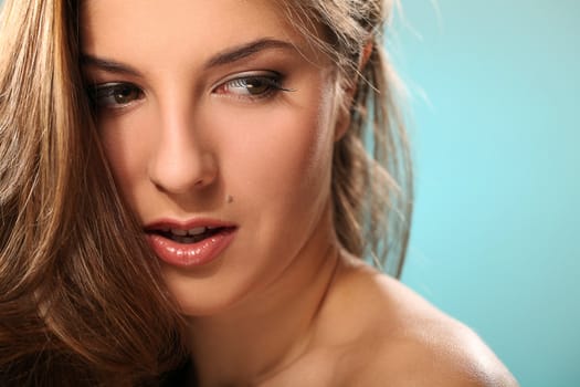 Portrait of young beautiful woman with long hair isolated over blue background