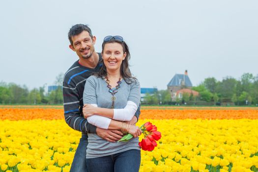 Young happy couple in the yellow tulip fields from the Netherlands