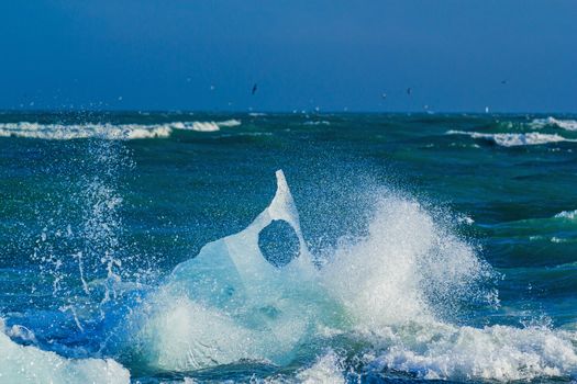 An Iceberg Being Broken By The Waves. Beautiful beach in the South of Iceland is full of icebergs from glaciers.