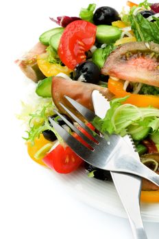 Arrangement of Vegetable Salad with Tomatoes, Yellow Bell Pepper, Leek, Black Olive, Cucumber, Lettuce and Olive Oil and Fork and Knife on White background