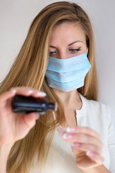 Woman in mask hand holding medicine health care syrup. Shallow depth of field.