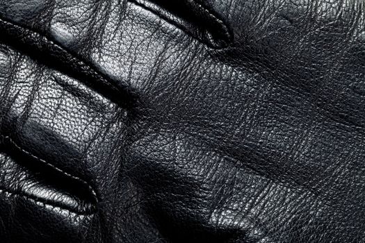 Black leather for background. Man glove. Macro shot
