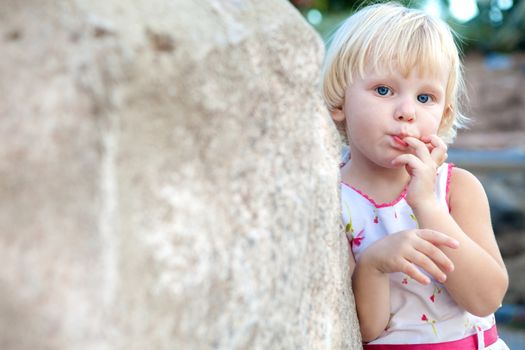 surprised girl sucking finger by the stone