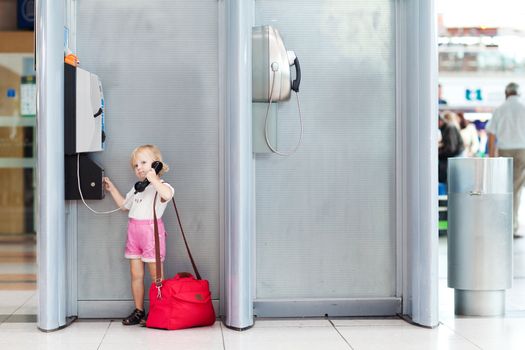 child with bag talking the phone in the airport