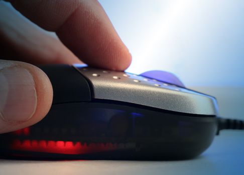 Extreme close-up of man holding computer mouse. Blue lighting effect applied.