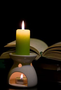 Candle and book on dark background