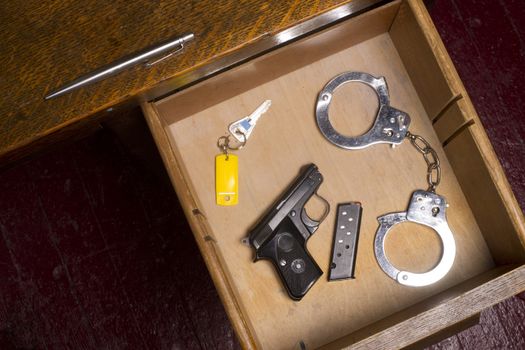 A desk housing pen, gun, key, and handcuffs