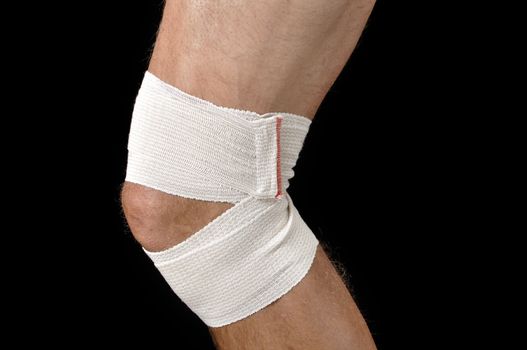 Closeup of male athlete with leg bandaged in sports wrap on black background