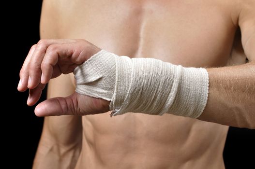 Closeup of wrist of shirtless male athlete with sports wrap on black background