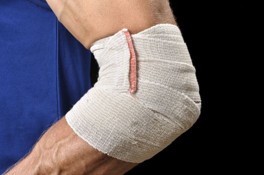 Closeup of athletic man's elbow bandaged with sports wrap on black background