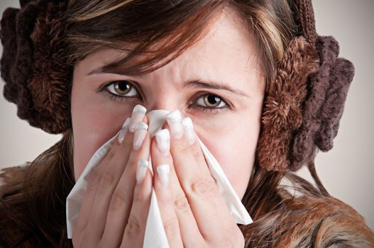 Pale sick woman with a flu, sneezing, in a dark background