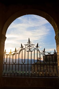 Sun sets over the Spainish mountains through an arch from Ronda.