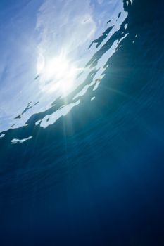 sun shines through the water in the red sea creating a beautiful blue water background.