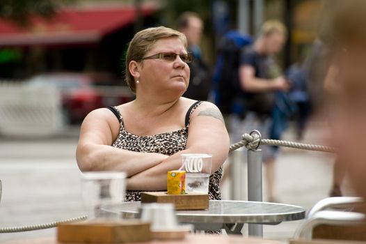 The single woman sits at a table in street cafe. Taken  in Helsinki, Finland on July 2012.