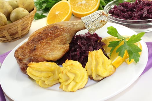 fresh fried Duck drumstick with duchess potatoes and red cabbage on a light background