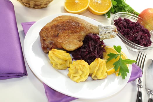 fresh Duck drumstick with duchess potatoes and red cabbage on a light background