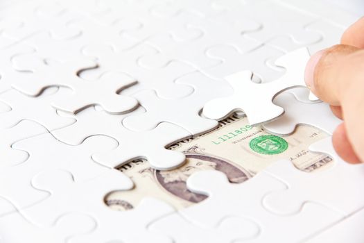 hand holding a puzzle piece, money concept