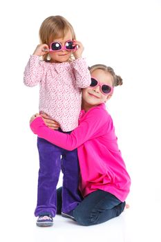 Two happy adorable smiling sisters in sunglasses. Isolated white background