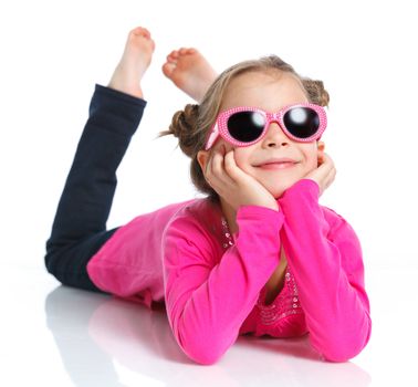 Little fashion girl lying in pink dress and sunglasses. Isolated white backround.
