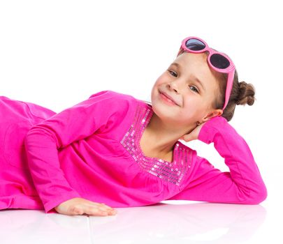 Little fashion girl lying in pink dress and sunglasses. Isolated white backround.