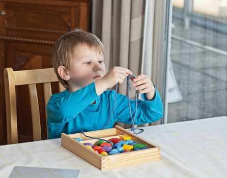 Little boy playing with colorful toys at home