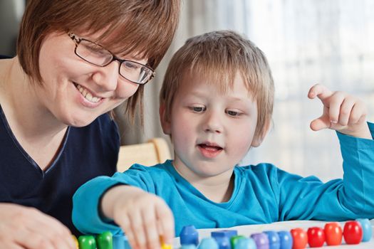 Mother and her little son playing colorful toys at home