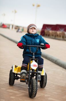 Little boy riding tricycle in a cold winter day