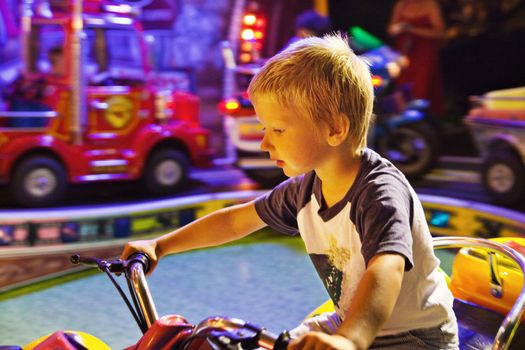 Little boy riding toy bicycle in amusement park