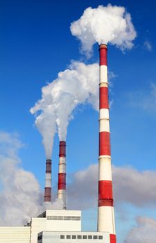 Smoking pipes of thermal power plant against blue sky
