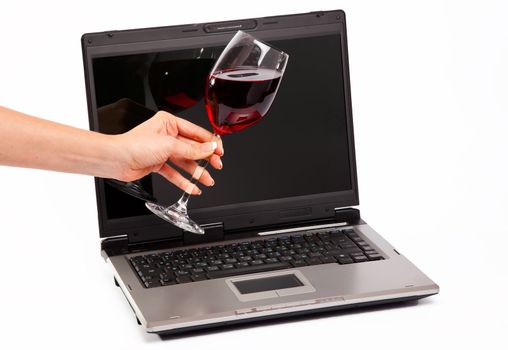 Glass of red wine on laptop on white background
