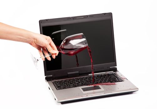 Wine spilled on laptop keyboard on white background