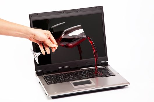 Red wine spilled on laptop keyboard on white background