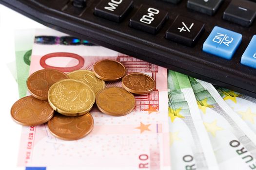 Euro coins and banknotes with a calculator isolated on white background