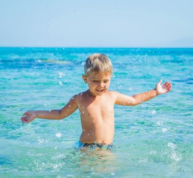 Portrait of young boy swimming and squirting in the transparent sea