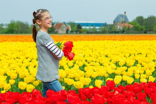 Young nice girl standing in red and yellow tulips field