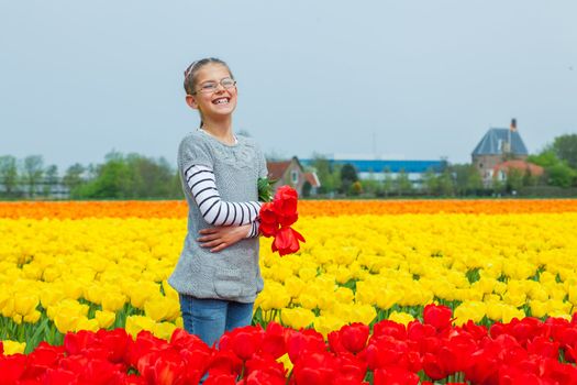 Young nice girl standing in red and yellow tulips field