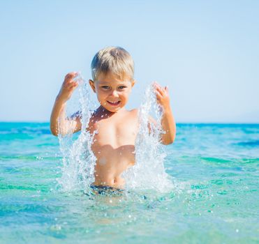 Portrait of young boy swimming and squirting in the transparent sea