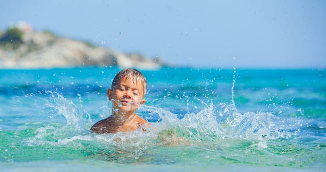 Portrait of young boy swimming and squirting in the transparent sea